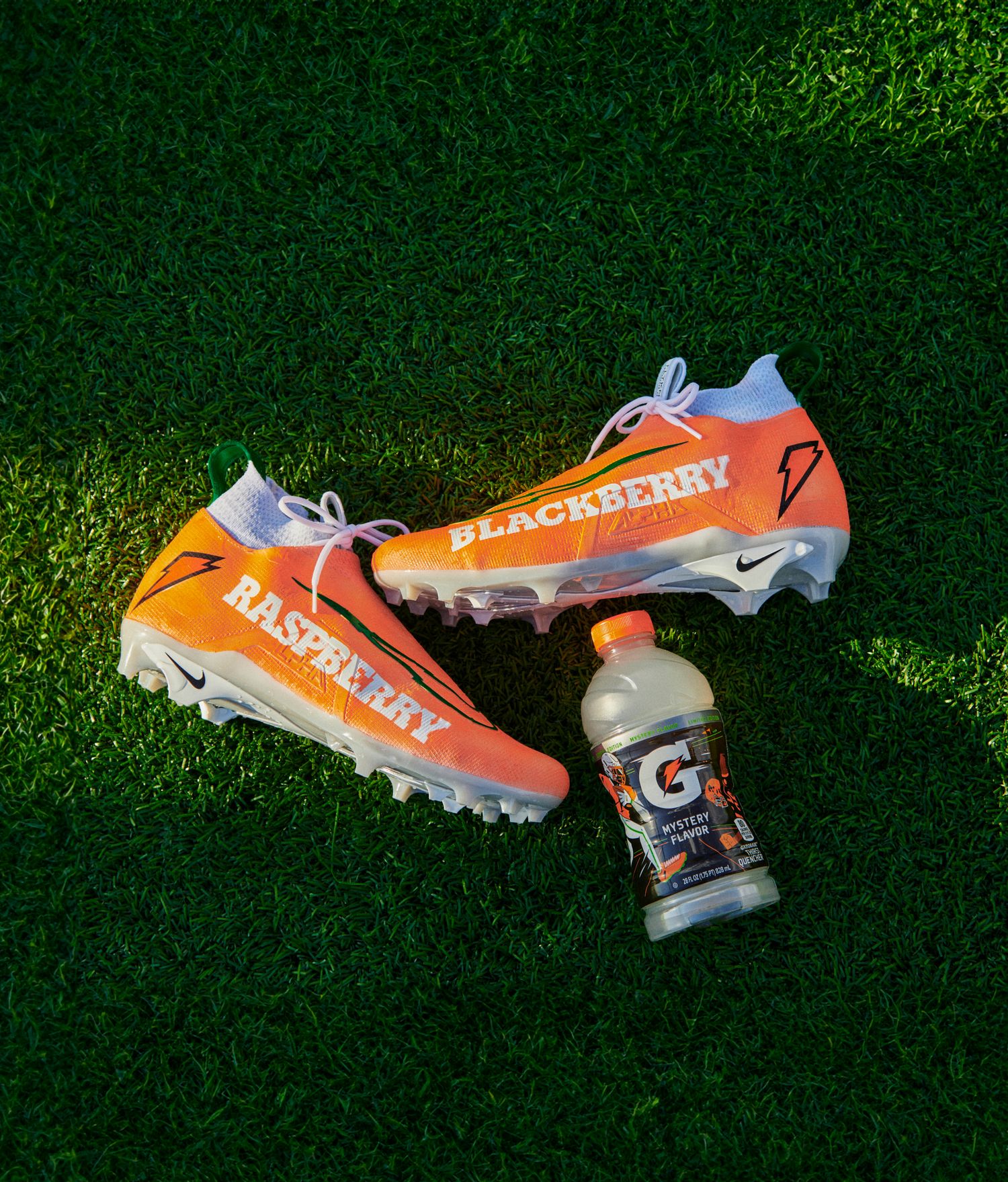 Shedeur Sanders orange and white Nike cleats next to a Gatorade bottle.